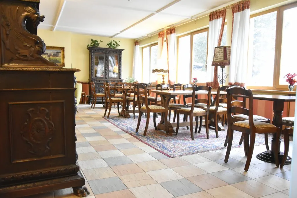 Sala interna con tavoli, sedie in legno e mobile antico intagliato