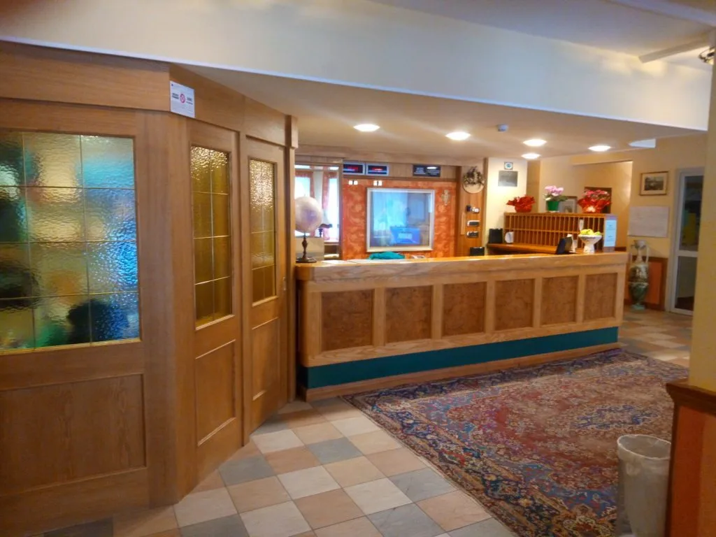 Reception dell'hotel con bancone in legno e pavimento a scacchi