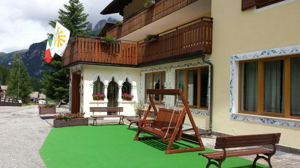 Dettaglio della terrazza con dondolo in legno, panchine e prato verde