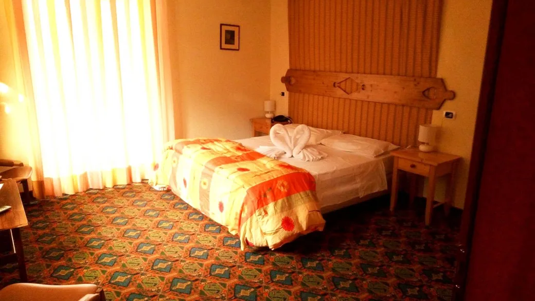 Camera matrimoniale con letto decorato, moquette colorata e luce naturale