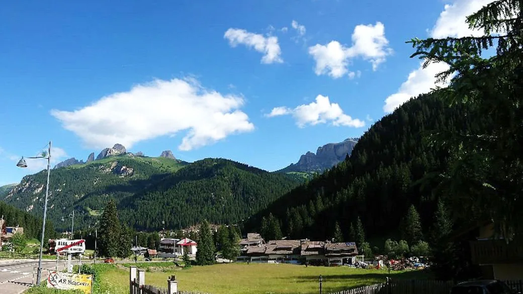 Panorama estivo delle montagne dolomitiche con prati verdi e cielo azzurro