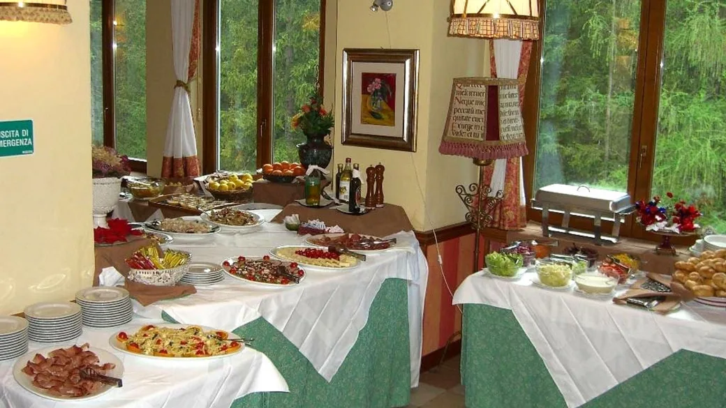 Buffet ricco di piatti e antipasti con vista sul bosco dalle finestre
