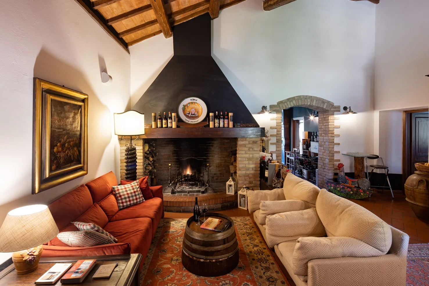 Sala soggiorno con grande camino acceso, divani e travi in legno a vista
