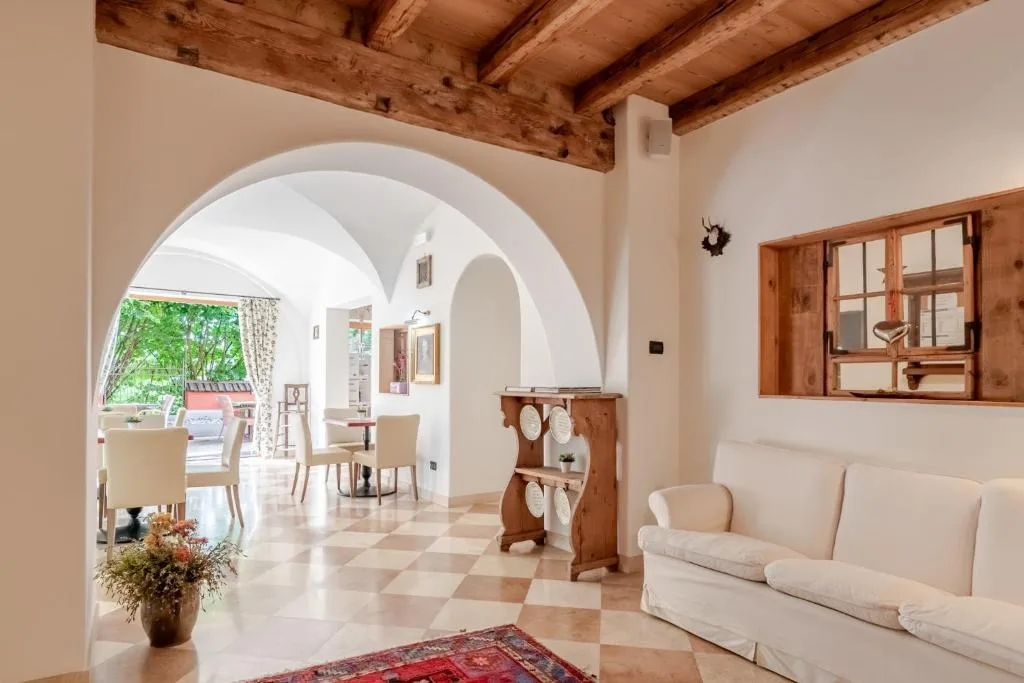 Soggiorno con divano bianco, archi e affaccio sulla sala ristorante