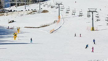 Pista da sci innevata con sciatori e impianto di risalita in una giornata di sole