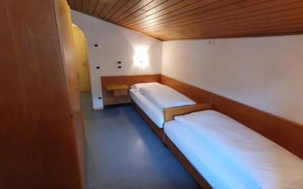 Camera mansardata con due letti singoli e soffitto in legno