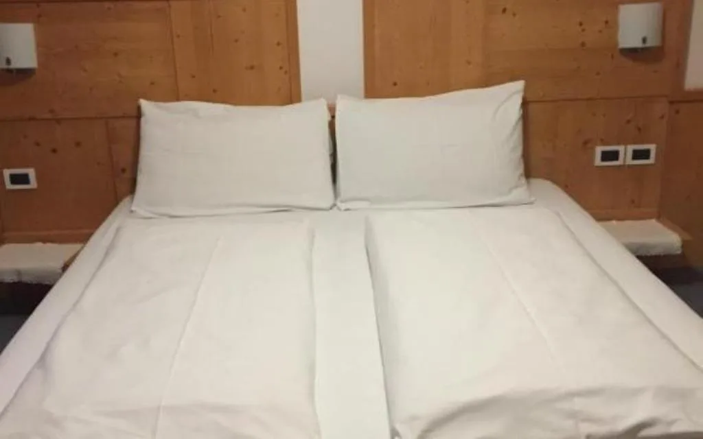 Letto matrimoniale con testiera in legno e biancheria bianca
