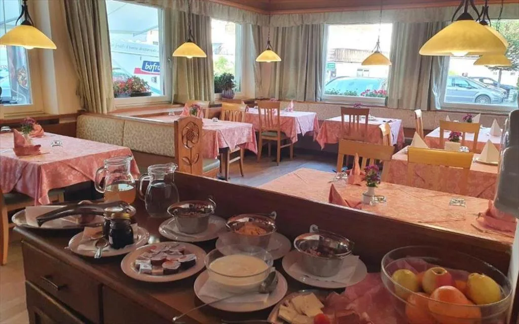 Sala colazione con buffet, tavoli apparecchiati con tovaglie rosa e lampade gialle