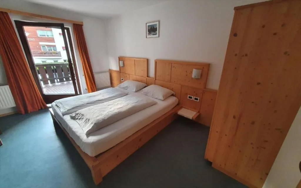 Camera matrimoniale con arredi in legno e uscita sul balcone
