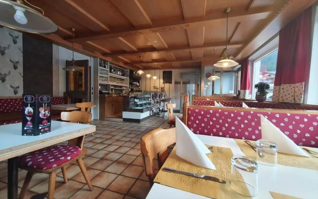 Sala ristorante con soffitto in legno, panche rosse e tavoli apparecchiati