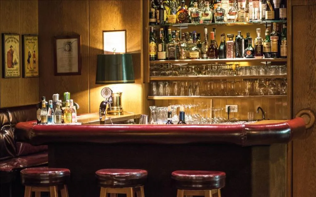 Bar dell'hotel in legno con sgabelli e ampia selezione di bottiglie