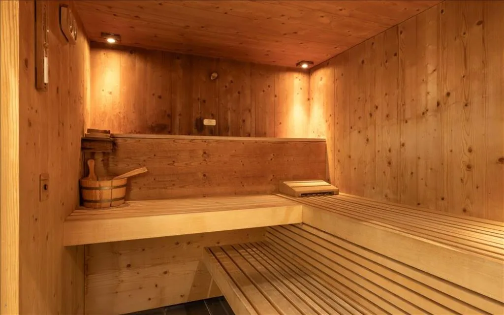 Sauna finlandese in legno con panche e secchiello tradizionale