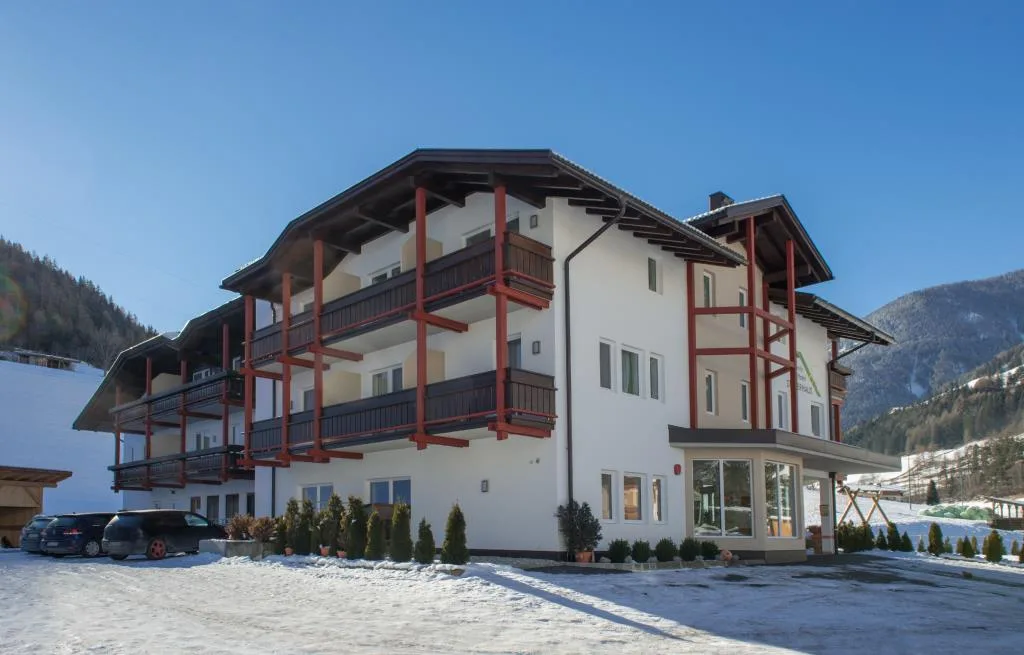 Esterno dell'hotel con balconi in legno e parcheggio innevato in inverno