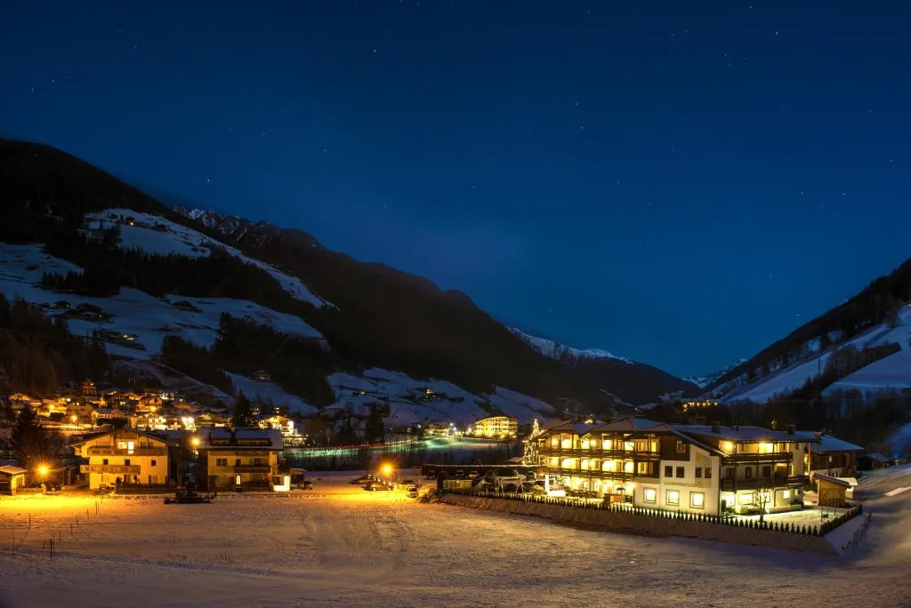 Veduta notturna del villaggio innevato con hotel illuminato tra le montagne