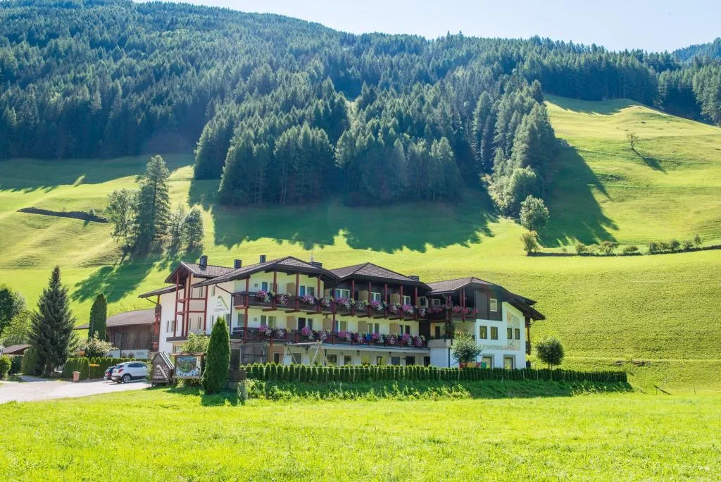 Hotel con balconi fioriti immerso in prati verdi e boschi in estate