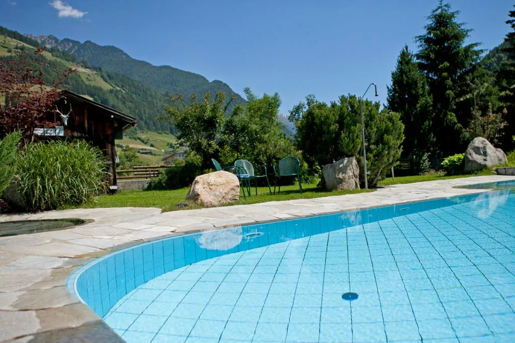 Piscina esterna dall'acqua azzurra con pavimentazione in pietra e vista sulle montagne