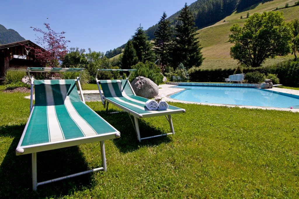 Lettini a righe verdi su prato accanto alla piscina esterna in ambiente montano