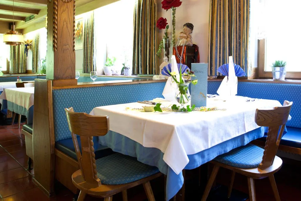 Angolo ristorante con panca blu, tavolo apparecchiato e decorazioni floreali