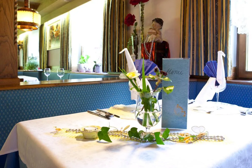 Tavolo del ristorante con menu, fiori e decorazioni su tovaglia bianca