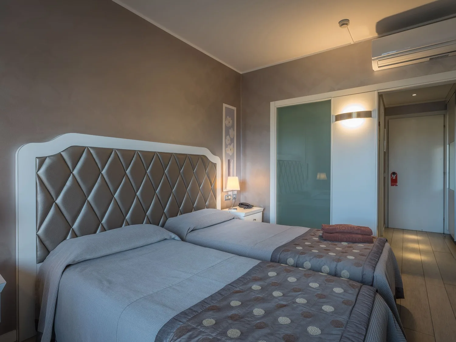 Camera con testiera imbottita trapuntata, letto matrimoniale e armadio a specchio
