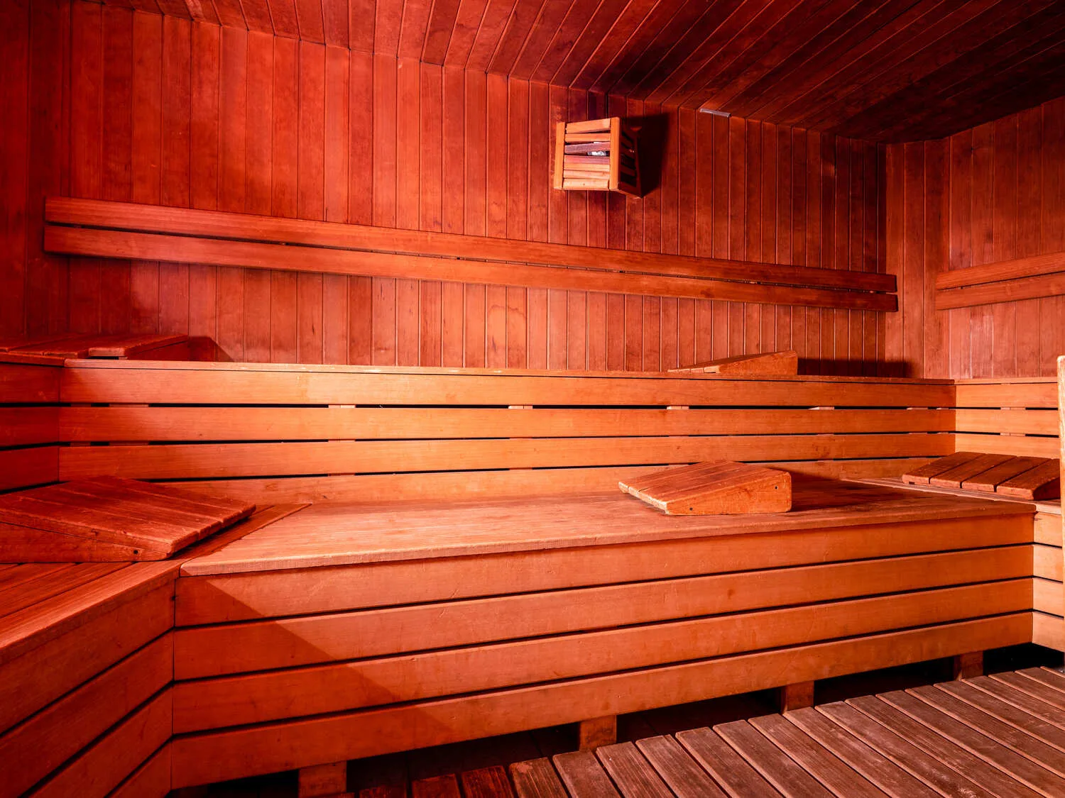 Sauna finlandese in legno con panche su più livelli e illuminazione calda