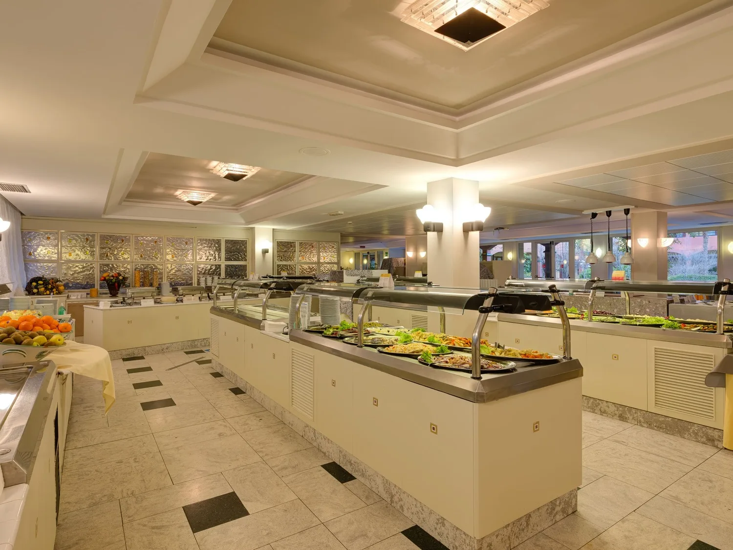 Sala ristorante a buffet con banchi self-service di piatti caldi e frutta fresca