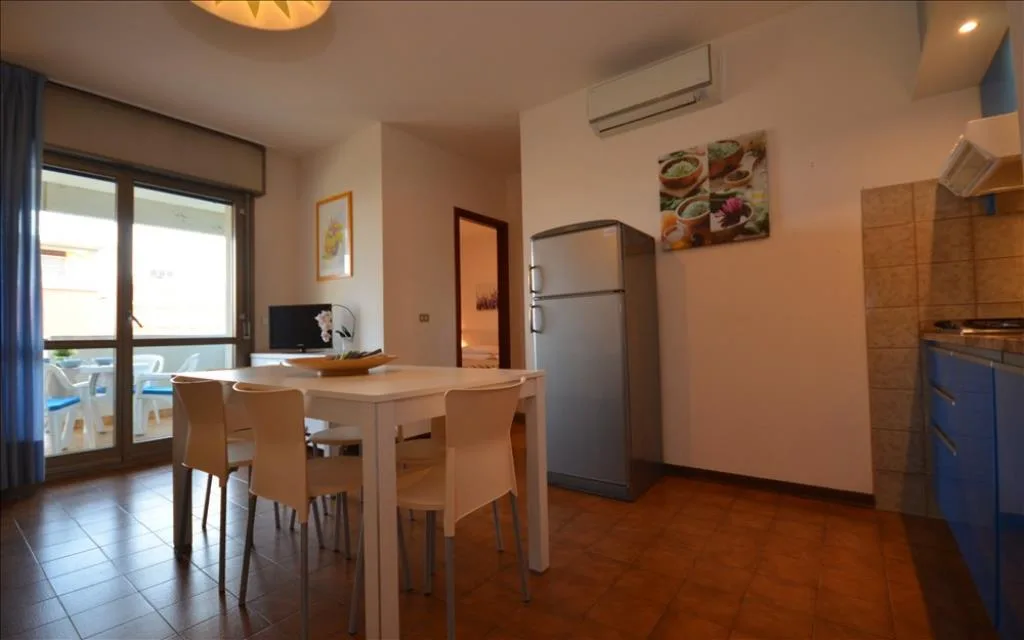 Soggiorno con angolo cottura, tavolo da pranzo e balcone