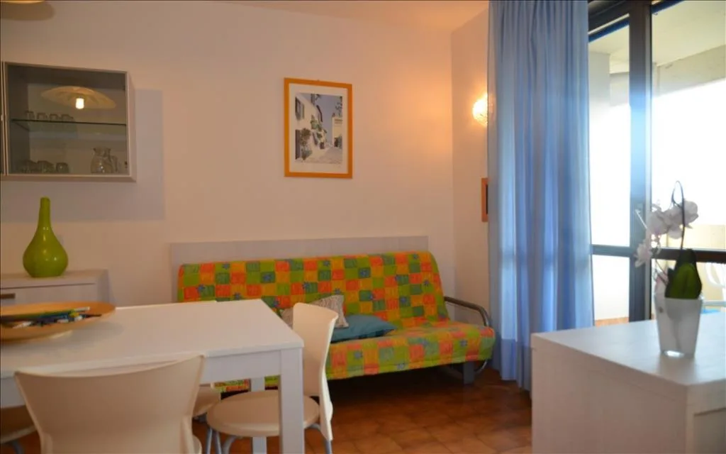 Soggiorno con divano colorato, tavolo bianco e tende azzurre
