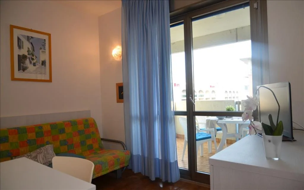 Zona living con divano letto colorato e accesso al balcone