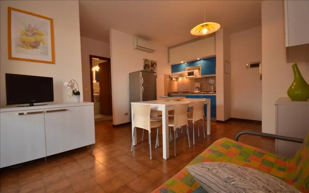Soggiorno con cucina blu, TV, tavolo da pranzo e divano