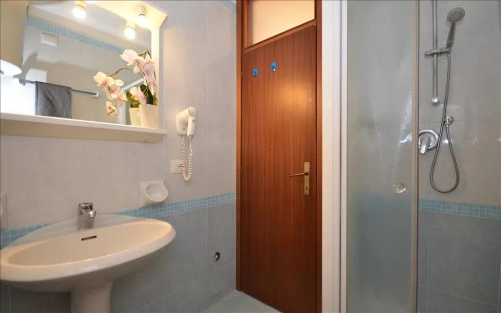 Bagno con lavabo, specchio, doccia e porta in legno