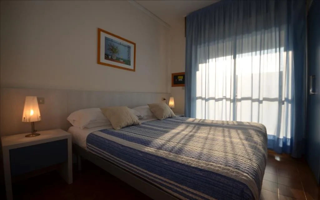 Camera matrimoniale con copriletto blu e ampia finestra