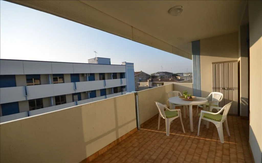 Balcone con tavolo e sedie bianche e vista sugli edifici