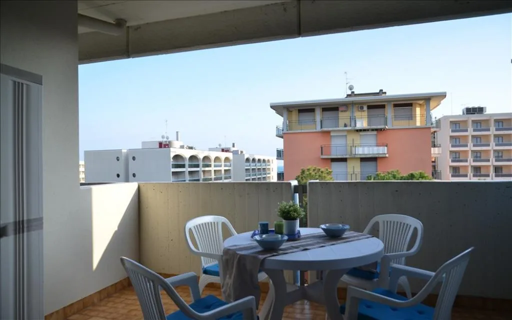 Terrazzo con tavolo rotondo e sedie bianche con vista sulla città