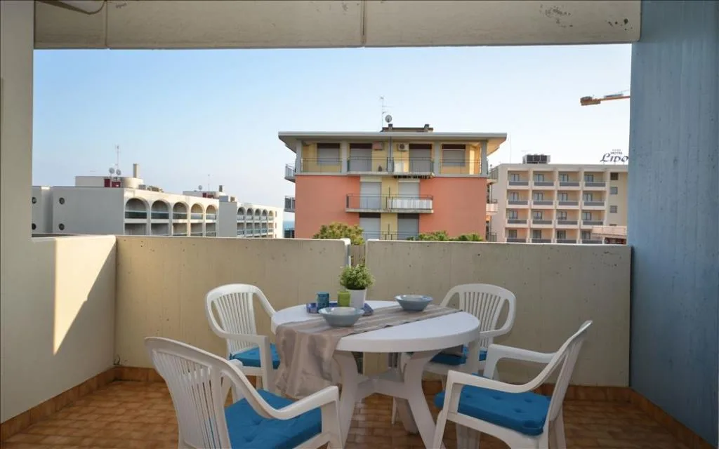 Terrazzo con tavolo e sedie bianche vista mare in lontananza