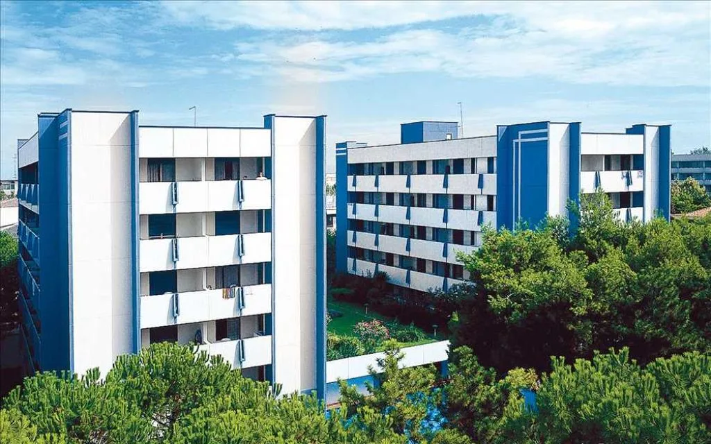 Vista esterna degli edifici bianchi e blu della residence tra il verde