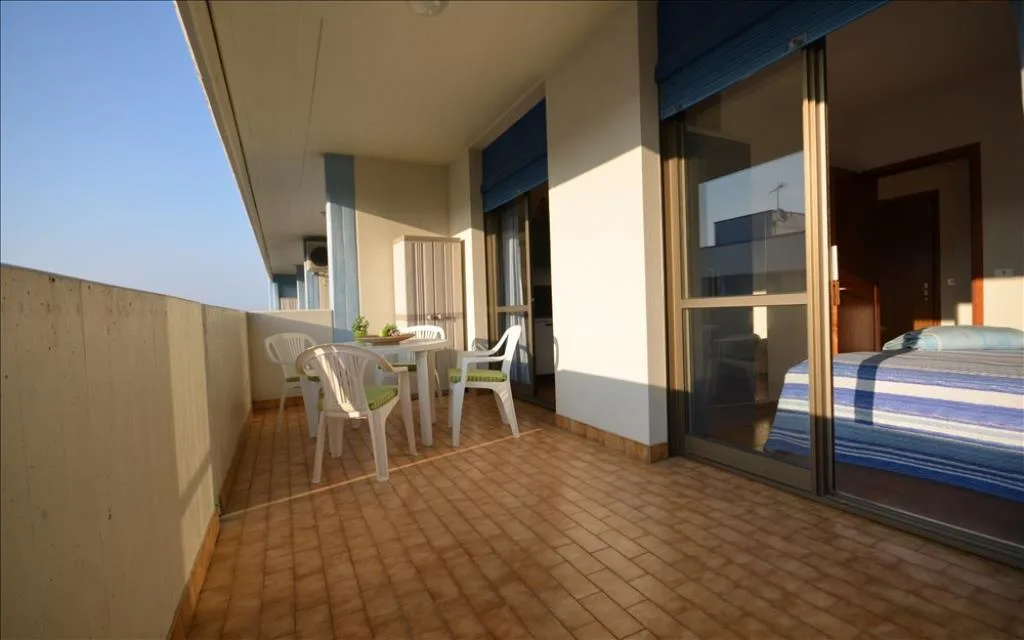 Ampio balcone piastrellato con tavolo, sedie e accesso alla camera