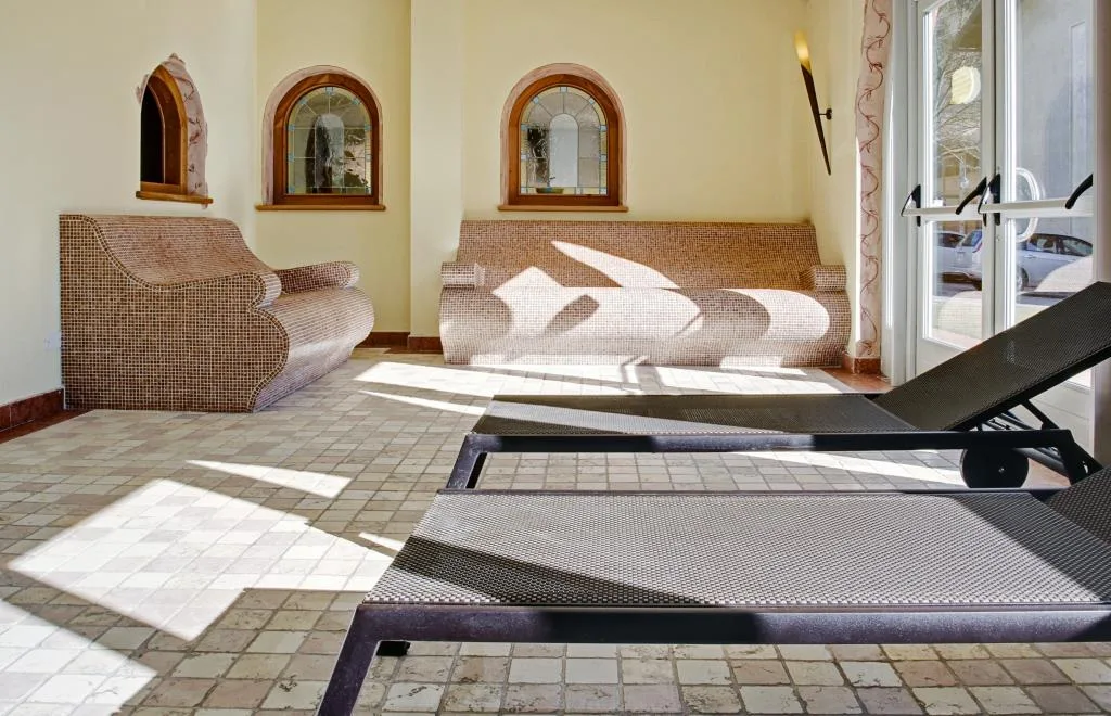 Zona relax della spa con lettini e panche in mosaico illuminate dalla luce naturale