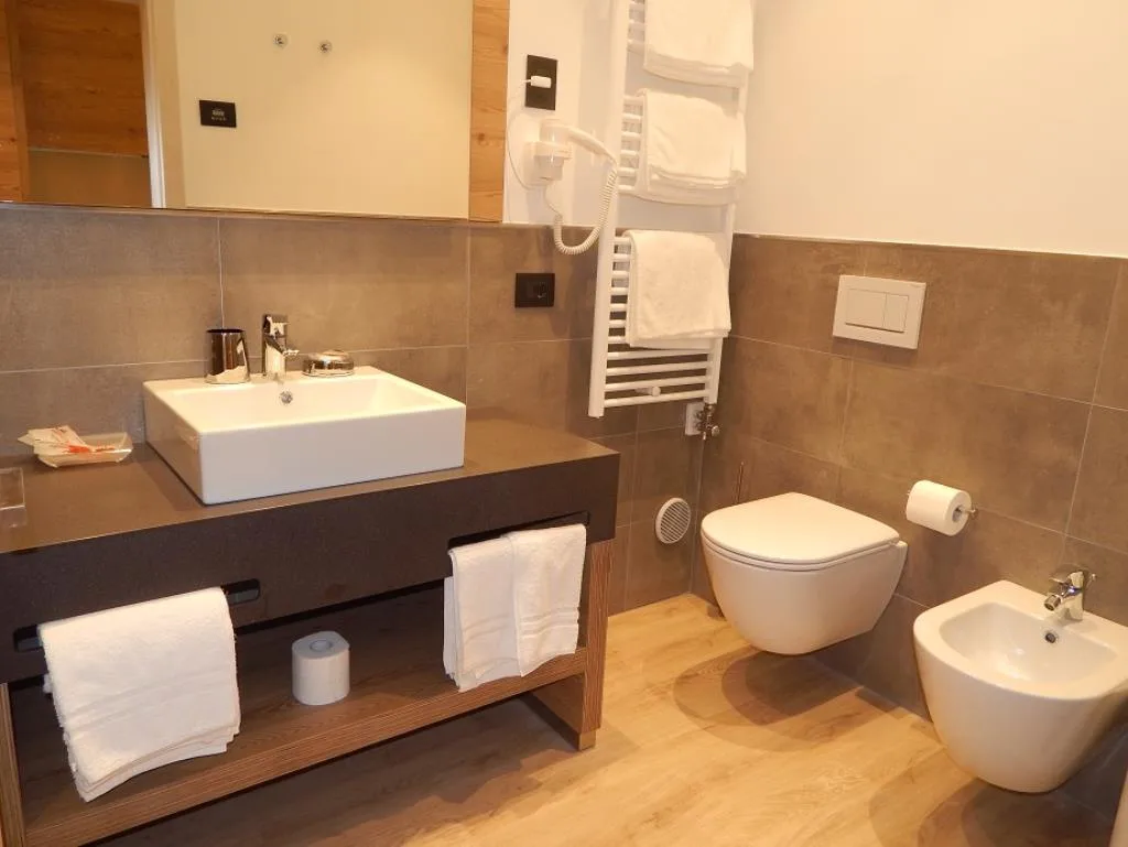 Bagno moderno con lavabo quadrato, WC, bidet e pavimento in legno