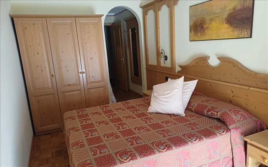 Camera con letto matrimoniale, armadio in legno e quadro alla parete