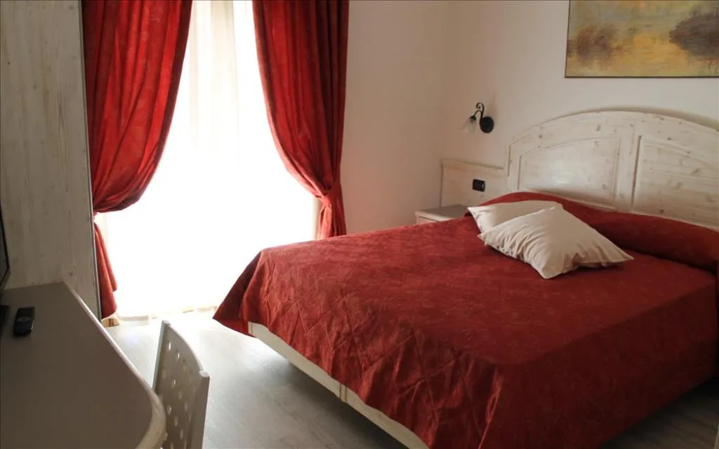 Camera matrimoniale con copriletto rosso e ampia finestra con tende rosse