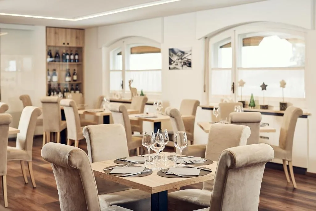 Sala da pranzo luminosa con tavoli apparecchiati e arredi chiari