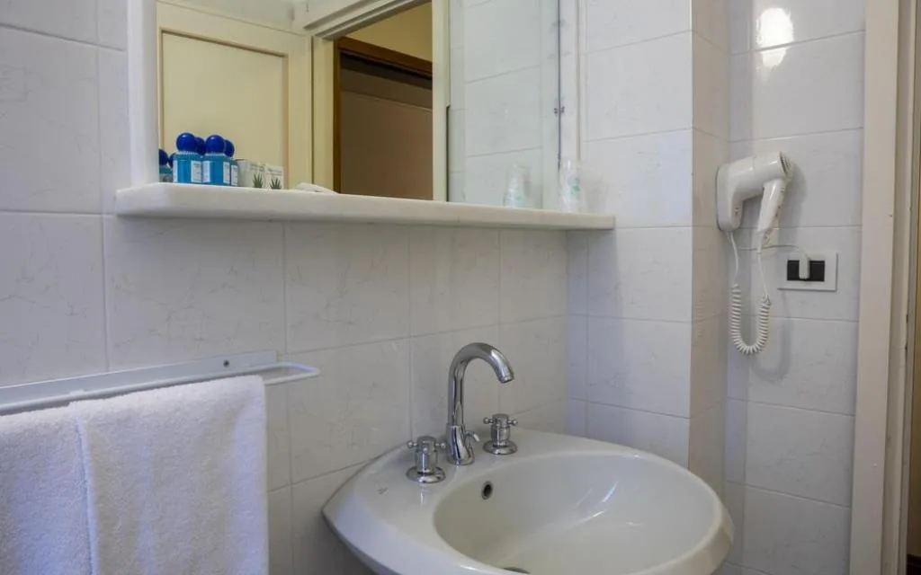 Bagno con lavabo, specchio, asciugacapelli e set di cortesia