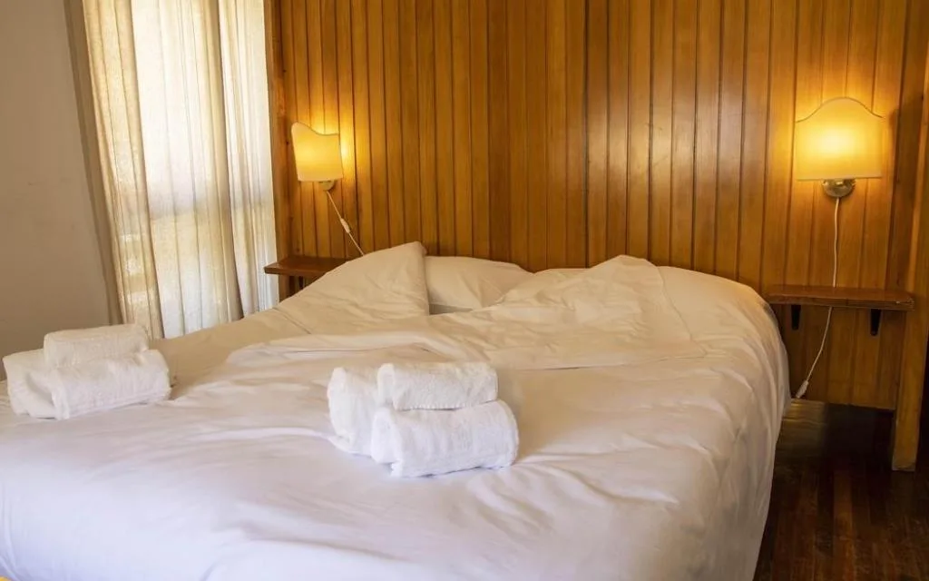 Letto matrimoniale con testiera in legno e lampade da parete