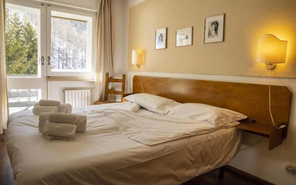 Camera con letto, parete gialla e finestra con vista sugli alberi