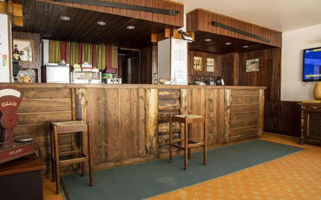 Bar interno rivestito in legno con sgabelli e TV a parete