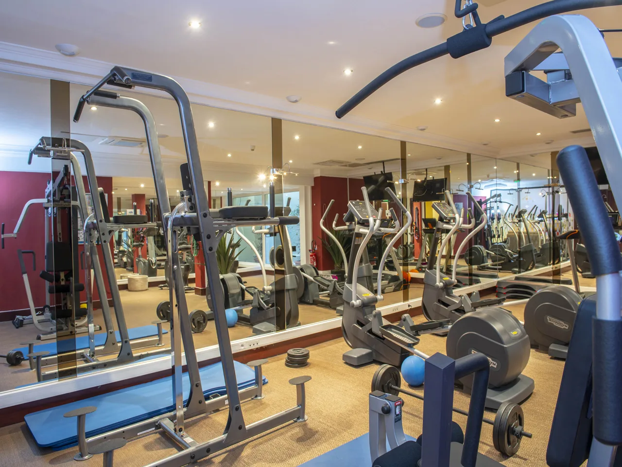 Palestra attrezzata con macchine cardio, pesi e grandi specchi alle pareti