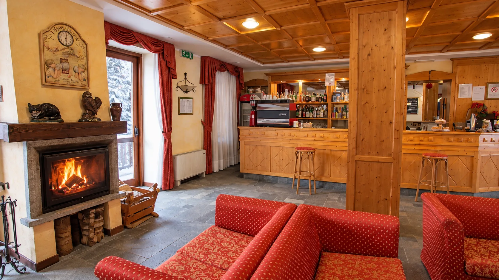 Area lounge con camino acceso, divani rossi e bar in legno