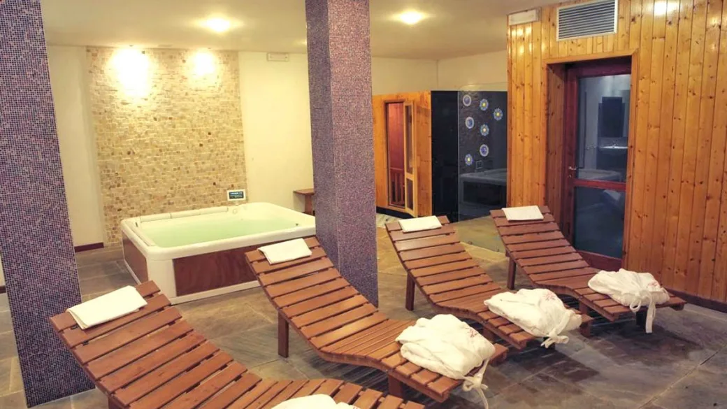 Area spa con vasca idromassaggio, lettini in legno e sauna