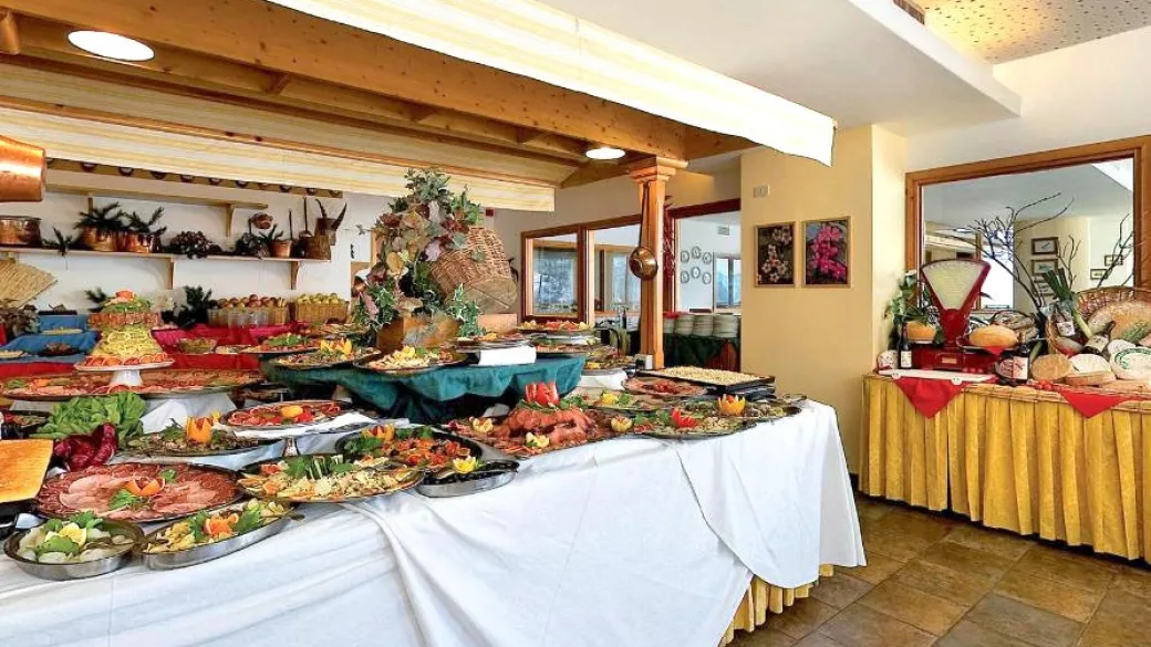 Ricco buffet con antipasti, salumi e piatti decorati su tavoli con tovaglie bianche